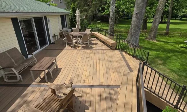 decatur-after-deck-boards-and-railing-replacement-aspect-ratio-1000-600 After view of updated lakefront deck with composite-style decking, dark railing, built-in bench seating, and outdoor furniture overlooking the yard