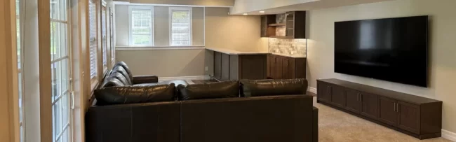 finished-basement-living-area-2-aspect-ratio-1920-600 Finished basement living area with leather sectional, wet bar, recessed lighting, carpet, patio doors, and large windows