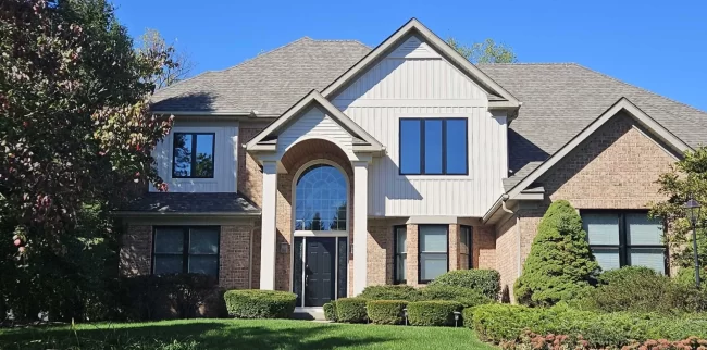 Exterior Home Update | Pennings Handyman Updated two-story home exterior with brick, white siding accents, black windows, and a refreshed front entry.