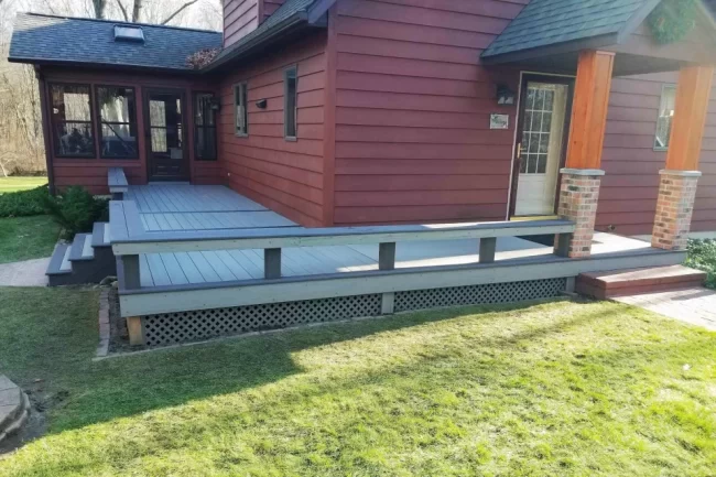front-porch-deck-aspect-ratio-960-640 Updated front porch deck with gray decking, built-in bench seating, lattice skirting, and steps leading to the home entry