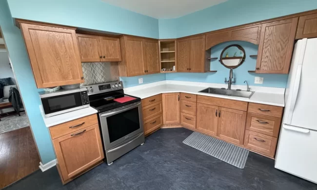 kalamazoo-after-kitchen-update-aspect-ratio-1000-600 After photo of a kitchen update with refreshed oak cabinets, white countertops, black slate-look flooring, stainless steel range, updated cabinet hardware, and blue accent walls