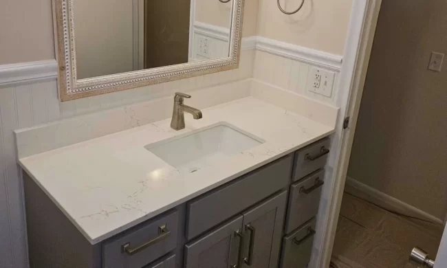 kalamazoo-bathroom-vanity-replacement-after-aspect-ratio-1000-600 After view of updated bathroom vanity with gray cabinetry, white countertop, framed mirror, and new vanity light fixture