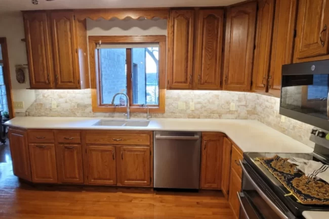 kitchen-countertop-update-1-aspect-ratio-960-640 Updated kitchen with wood cabinets, light countertops, tile backsplash, under-cabinet lighting, and stainless steel appliances