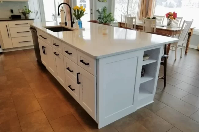 kitchen-island-rebuild-white-cabinets-aspect-ratio-960-640 Rebuilt white kitchen island with black hardware, sink, dishwasher, and open shelving in a finished kitchen