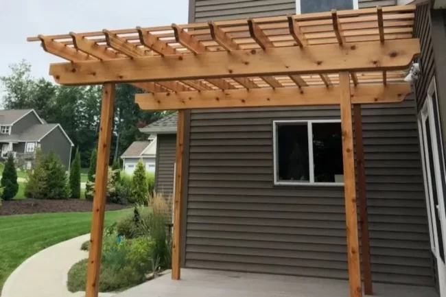 new-wood-pergola-patio-1-aspect-ratio-960-640 Wood pergola built over a backyard patio next to a home with brown siding