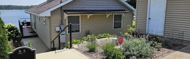 outdoor-handrail-installation-aspect-ratio-1920-600 Lakefront home exterior with new handrail on stairs, metal awning, garden landscaping, and water view in the background