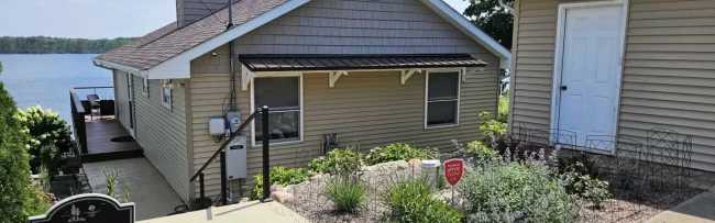 outdoor-handrail-installation-aspect-ratio-1920-600 Lakefront home exterior with new handrail on stairs, metal awning, garden landscaping, and water view in the background