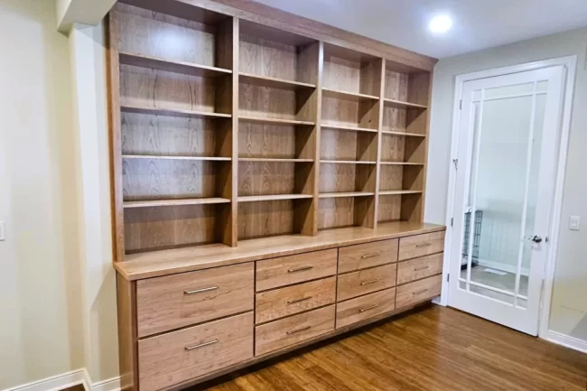 vicksburg-custom-built-in-shelving-drawers-1-aspect-ratio-960-640 Custom wood built-in shelving with lower drawers installed in a finished room